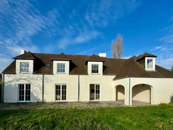 Façade blanche d'une villa de standing à Lasne, avec lucarnes et arcades