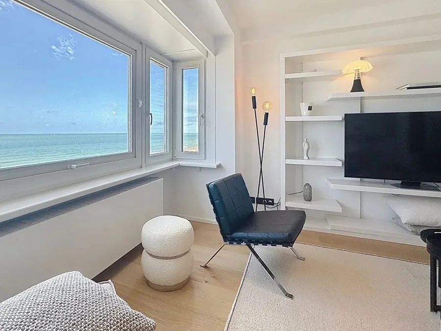Séjour lumineux d'un penthouse à Westende, avec grande baie vitrée sur la mer du Nord